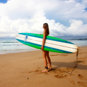 A girl on the beach with a big surfboard